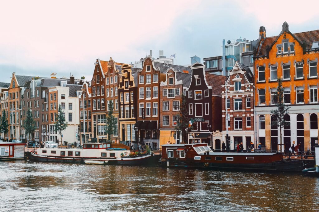 Colorful canal houses by the water. Amsterdam, Netherlands - Photo by Nastya Dulhiier on Unsplash