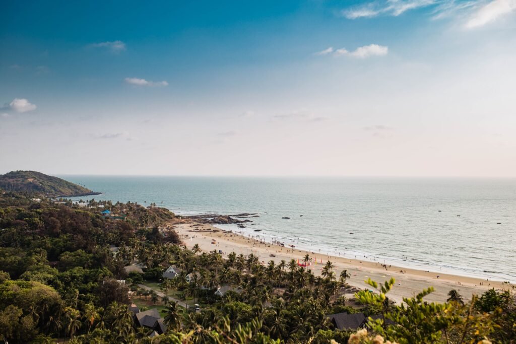 Best Monsoon Road Trips in India. Road Trip - Mumbai to Goa — The Coastal Classic. A beautiful aerial view of Mandrem Beach, Goa, with lush greenery and a serene coastline.